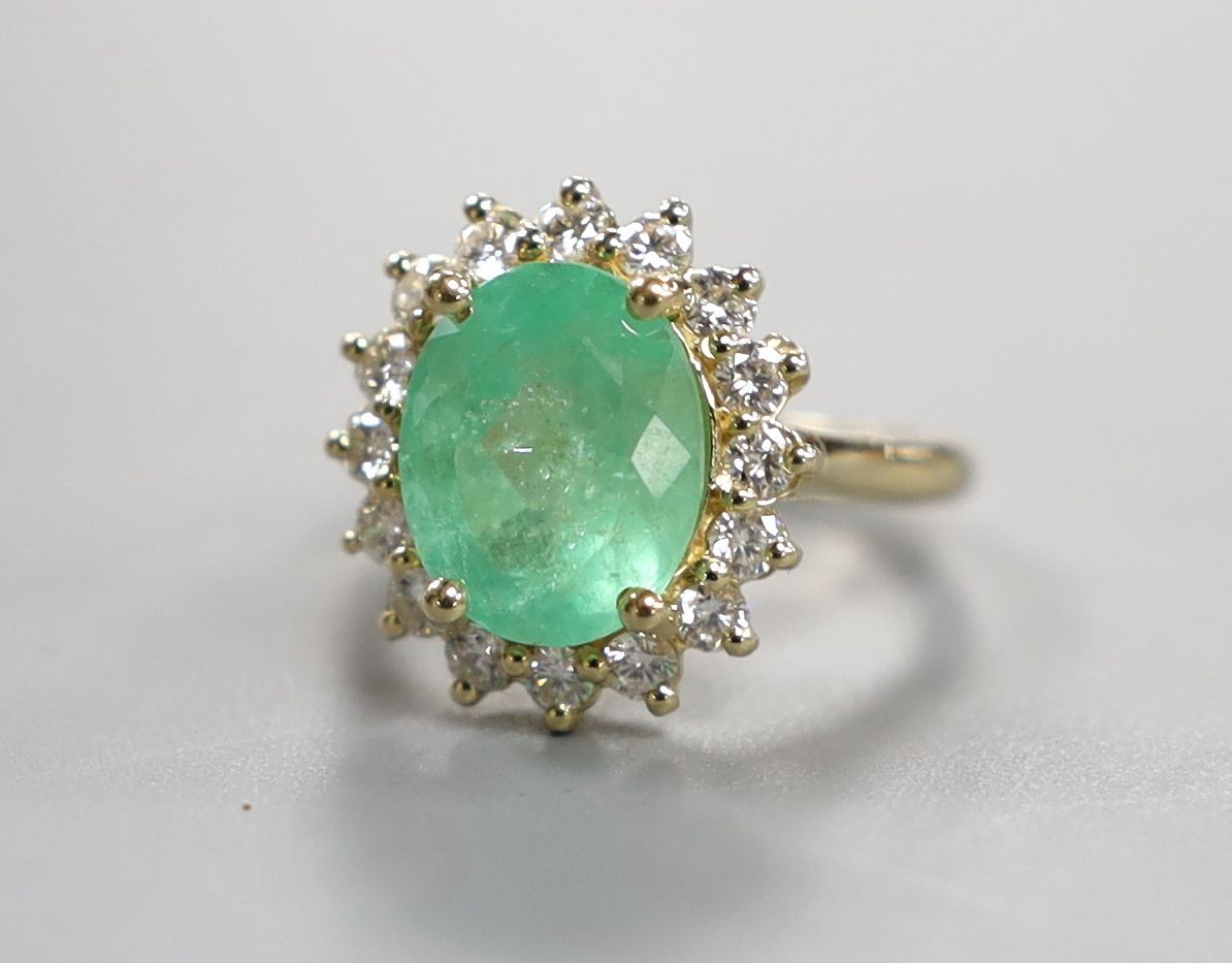 A modern 14k yellow metal, emerald and diamond set oval cluster ring, size M, gross weight 5.9 grams, with accompanying G.A.S. certificate dated 6/7/2016 estimating the emerald to weigh approximately 4.67ct.